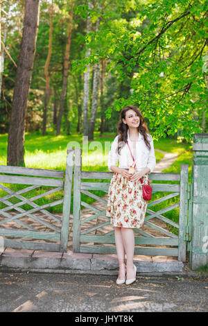 Portrait of beautiful young women standing against a fence looking at camera while eating ice cream. Stock Photo