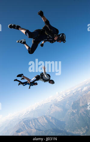 Four skydivers lining up on a tracking jump above Locarno, Switzerland with the Alps in the background Stock Photo