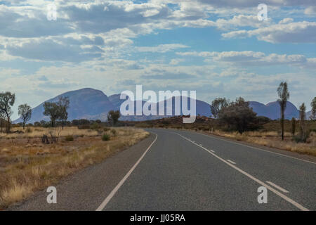 Kata Tjuta in the semi shaded afternoon sun,view from the main road, cloudy blue sky, red, dry, desert landscape, horizontal aspect. Stock Photo