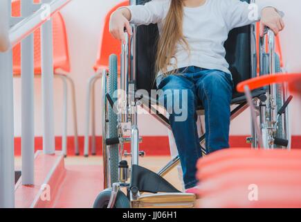 Disabled Girl on a Wheelchair Inside the Clinic Hallway. Disability Photo Concept. Stock Photo