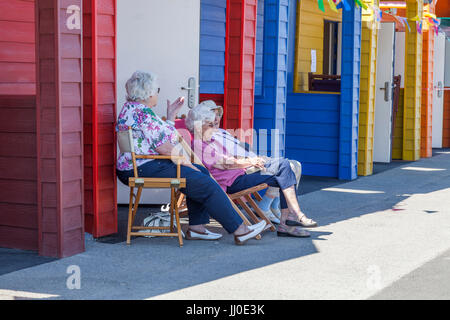 Three mature women sat on chairs outside a beach hut at Saltburn by the Sea,England,UK Stock Photo