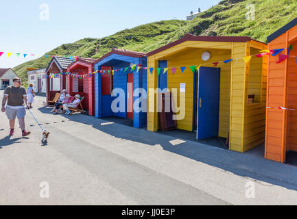 A man walking his dog past colourful beach huts at Saltburn by the Sea,England,UK Stock Photo