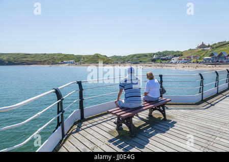 A man and woman sat on a bench on the pier looking out to sea at Saltburn by the Sea,England,UK Stock Photo