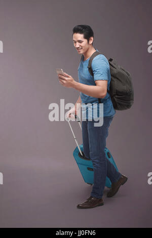 Traveler asian man with backpack using smartphone over dark background Stock Photo