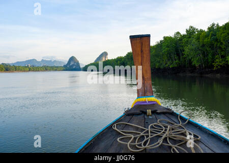 Bow of a traditional Thai longtail boat navigating upstream Krabi River towards the Khao Kanab Nam limestone outcrops, Krabi Province, Thailand. Stock Photo