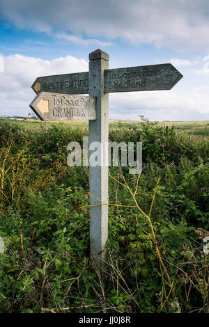 A wooden signpost on a footpath giving directions to West Pentire and Coast Path. Newquay, Cornwall. Stock Photo