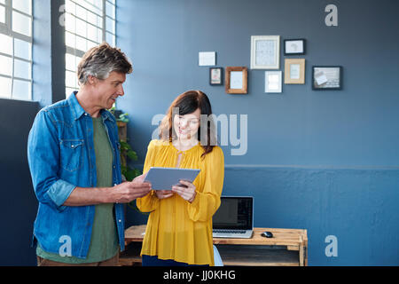Smiling colleagues talking together over a tablet in an office Stock Photo
