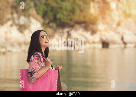 Young happy woman on vacation enjoying the sunrise on the beach Stock Photo