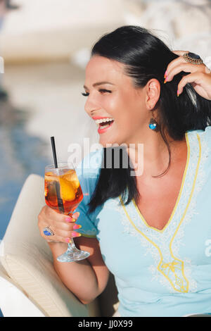 Happy young woman holding a glass of cocktail near the yacht marine, selective focus Stock Photo