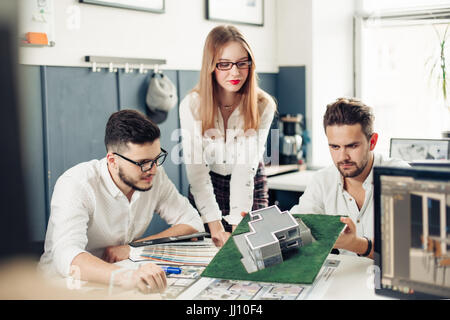 Close up of hands of professional architects discussing the project. They are standing near the blueprint. The man is holding a pencil and pointing it Stock Photo