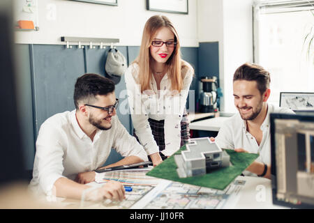 Close up of hands of professional architects discussing the project. They are standing near the blueprint. The man is holding a pencil and pointing it Stock Photo