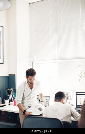 A young man with a suit reading a magazine. Hey the news that I am reading is excellent. Copy space on the magazine is for your text. Stock Photo
