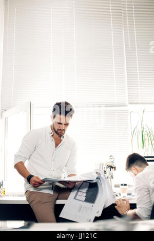 A young man with a suit reading a magazine. Hey the news that I am reading is excellent. Copy space on the magazine is for your text. Stock Photo