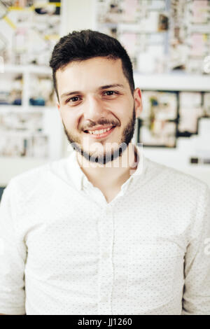 Portrait of a smart young man standing with arms crossed against blue background Stock Photo