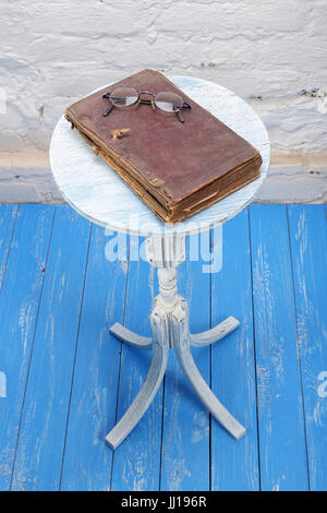 Retro style - Vintage Bible and Glasses on a old flowers stand on a wooden blue and a white brickwork background. Stock Photo