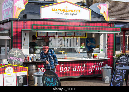 Old man in front of fish & chips and seafood stand in the city Oban, Argyll and Bute, Scotland, UK Stock Photo