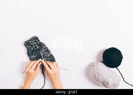 Female hands knit woolen socks on a white background, top view Stock Photo
