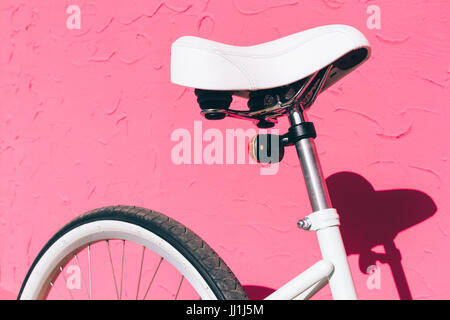 White saddle of a female city bicycle against a background of a pink wall, close-up Stock Photo