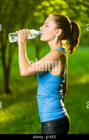 Young woman drinking water after fitness exercise Stock Photo