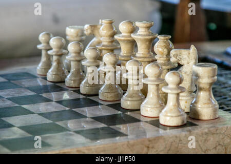 Stone carved chess pieces on chessboard. Shallow DOF, focus on pieces in the middle. Stock Photo