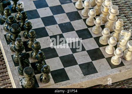 Stone carved chess pieces on chessboard. Stock Photo