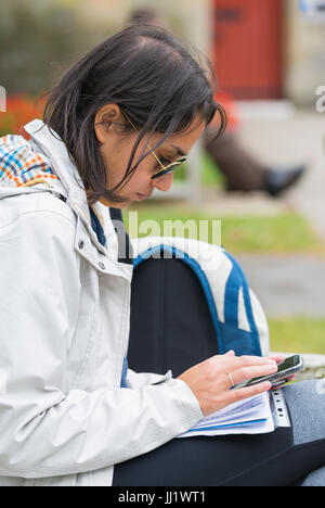 Woman sitting down using her smartphone. Sitting texting. Stock Photo