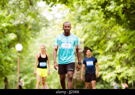 Group of young athletes prepared for run in green sunny park. Stock Photo