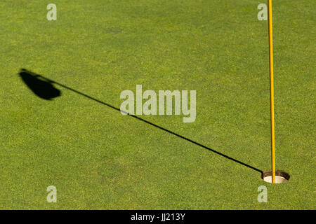 Close up of golf hole with shadow of flag on Green. Stock Photo