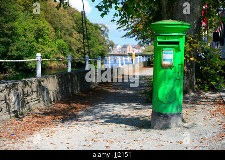 Bright green Irish post letter mail box on quiet lane. Stock Photo