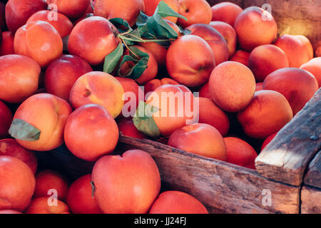 Peaches and nectarines in a wooden crate at an outdoor Farmer's Market Stock Photo