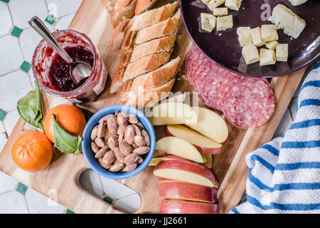 Simple rustic local organic lunch for two on a tiled table with a striped towel featuring bread and cheeses and meats Stock Photo