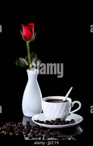 Composition of coffee and red rose on a black reflective background. Studio shot Stock Photo