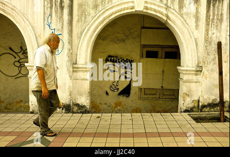 An elderly Chinese man walks past an old building in the city centre of Kuala Lumpur, Malaysia Stock Photo