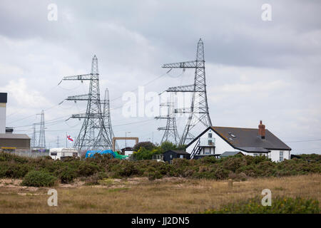 A solitary house sits amongst electricity pylons on the Dungeness nature reserve, power station, Kent cloudy day Stock Photo