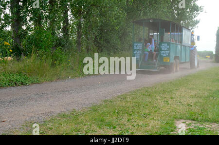 Farm tractor transporting fruit and vegetable picking public around a Pick Your Own farm in West Sussex, UK Stock Photo