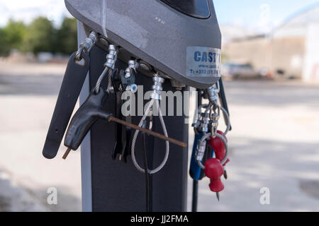 Tools attached by steel cables for repairing bicycles on a bike rack at a roadside filling station in Ireland.