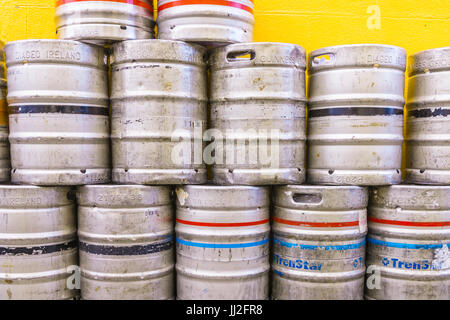 Aluminium beer kegs stacked up against a painted orange wall at an Irish pub. Stock Photo