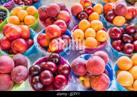 Closeup of many summer fruit in baskets in farmers market on display, including peaches, plums, nectarines and apricots Stock Photo