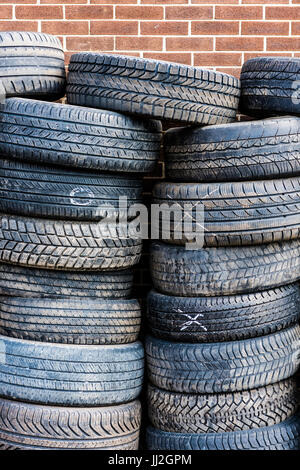 Pile of many old, used tires against brick wall Stock Photo