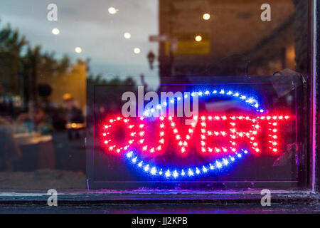 French ouvert open sign for store shop or restaurant glowing in the evening with window reflection Stock Photo