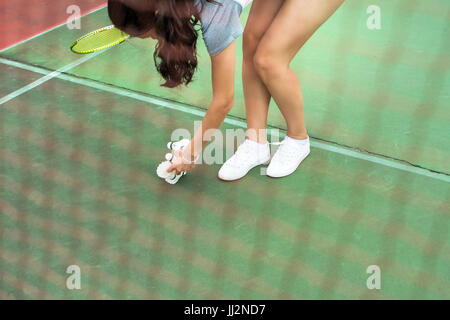 Girl collecting badminton ball behind the net Stock Photo