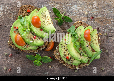 Avocado toast, cherry tomato on old paint wooden background. Stock Photo