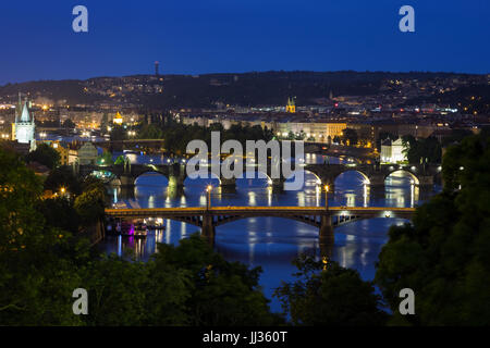 Lit buildings and bridges over Vltava River in Prague, Czech Republic, viewed slightly from above at night. Stock Photo