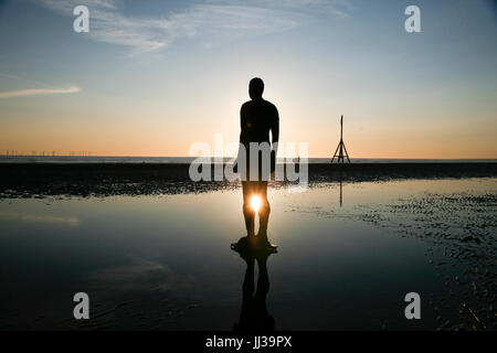 Crosby, UK. 17th July 2017. UK Weather. Clear skies at the end of a warm sunny day as the sun sets over Anthony Gormley's 'Another Place' art installation, featuring iron-clad figures fixed onto Crosby beach. Premos/Alamy Live News Stock Photo