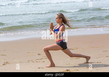 Bournemouth, Dorset, UK. 18th July, 2017. UK weather: warm sunny, but blowy, start to the day at Bournemouth beaches. Visitors head to the seaside to enjoy the sunshine. Jane visits Bournemouth for a couple of day and practises her yoga-type positions on the seashore. Credit: Carolyn Jenkins/Alamy Live News