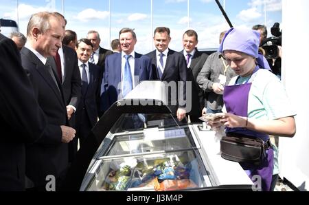 Zhukovsky, Russia. 18th July, 2017. Russian President Vladimir Putin, left, stops to buy an ice cream from a vendor during a visit to the International Aviation and Space Show known as the MAKS 2017 July 18, 2017 in Zhukovsky, Russia. A variety of new Russian aircraft including the new MiG-35 multipurpose fighter and Sukhoi T-50 stealth fighter were on display at the show. Credit: Planetpix/Alamy Live News Stock Photo