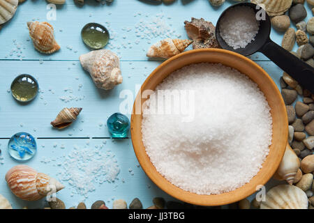 large wooden bowl with mineral sea salt with black scoop filled with salt on light blue painted wooden desk great as background for summer vacation tr Stock Photo