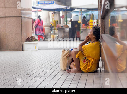 MALAYSIA, KUALA LUMPUR, OCT 03 2015, Older woman sitting on a street in the city center Stock Photo
