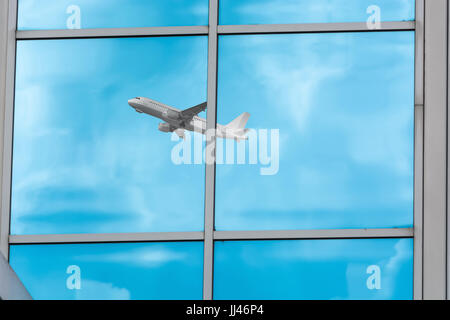 Beautiful glass building facade with reflections of an airplane during startup. Stock Photo