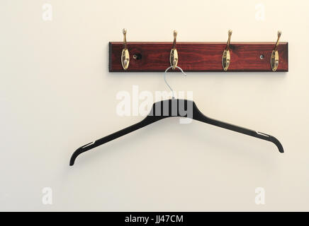 An empty clothes hanger hung on a brass coat hook Stock Photo